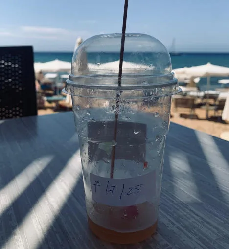 bicchiere in plastica e sullo sfondo la spiaggia